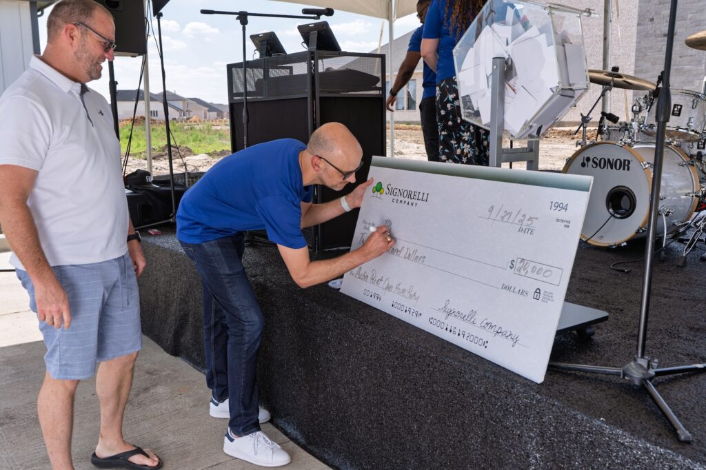 Roger Leavitt watches as Todd Hamilton signs the $20,000 home giveaway check at Austin Point’s Open House.