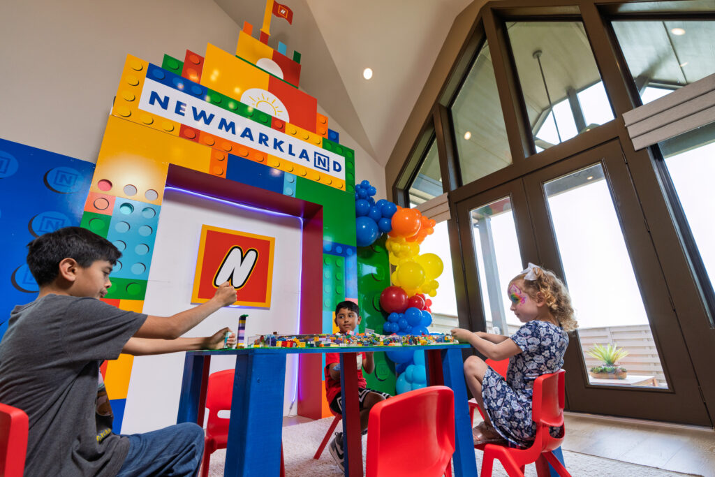 Children playing with LEGO bricks at Newmark Homes’ model home during Austin Point Open House Party.