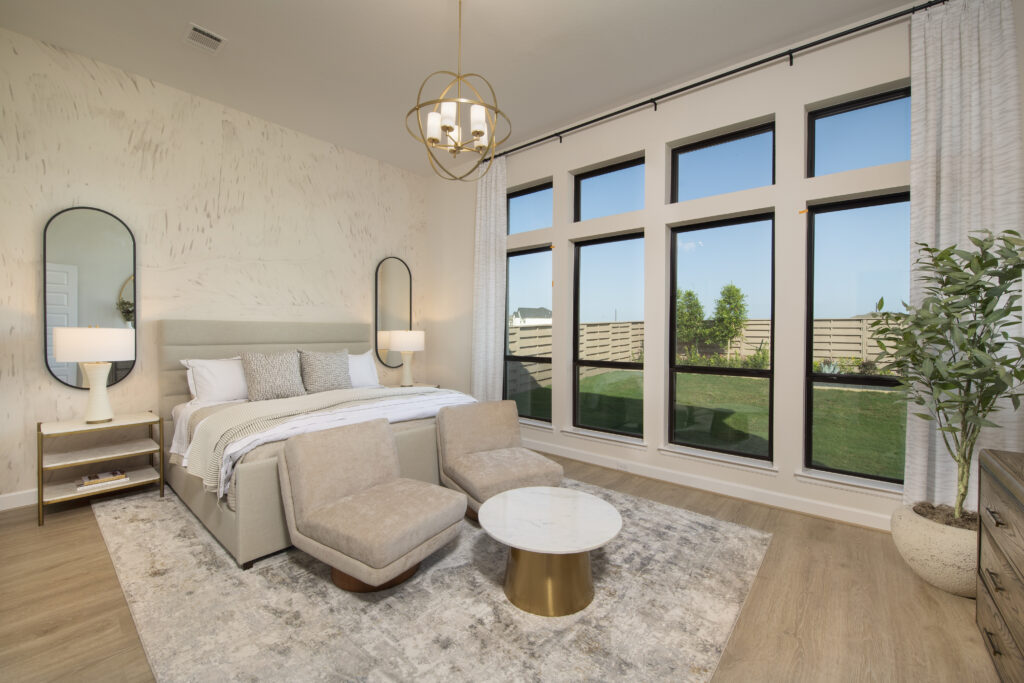 Primary bedroom with large windows and sitting area in Perry Homes 60' model home at Austin Point