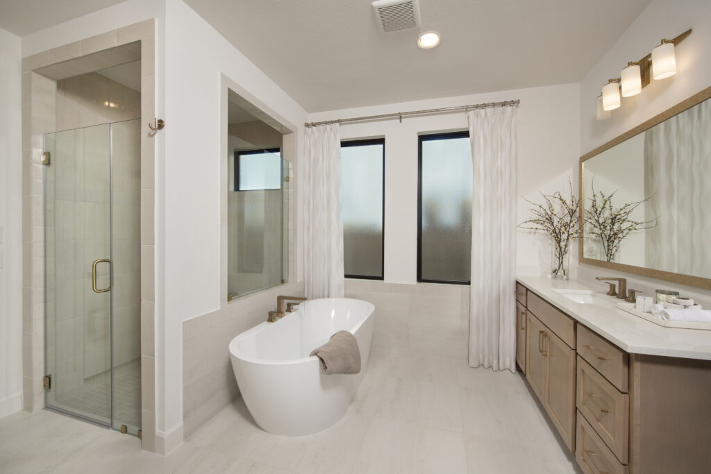 Modern primary bathroom with freestanding tub and walk-in shower in Perry Homes 60' model at Austin Point