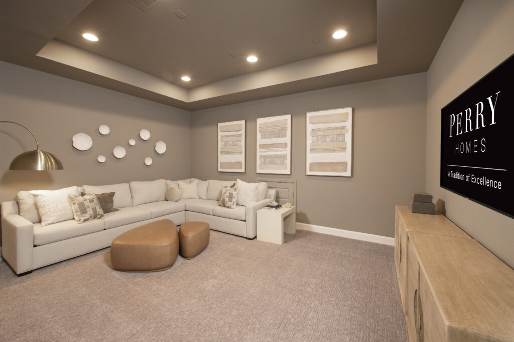 Cozy media room with sectional sofa and large screen in Perry Homes model at Austin Point.