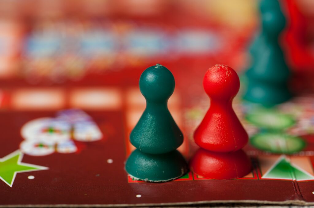 Close-up of red and green game pieces on a holiday-themed board game, symbolizing casual and inclusive party activities