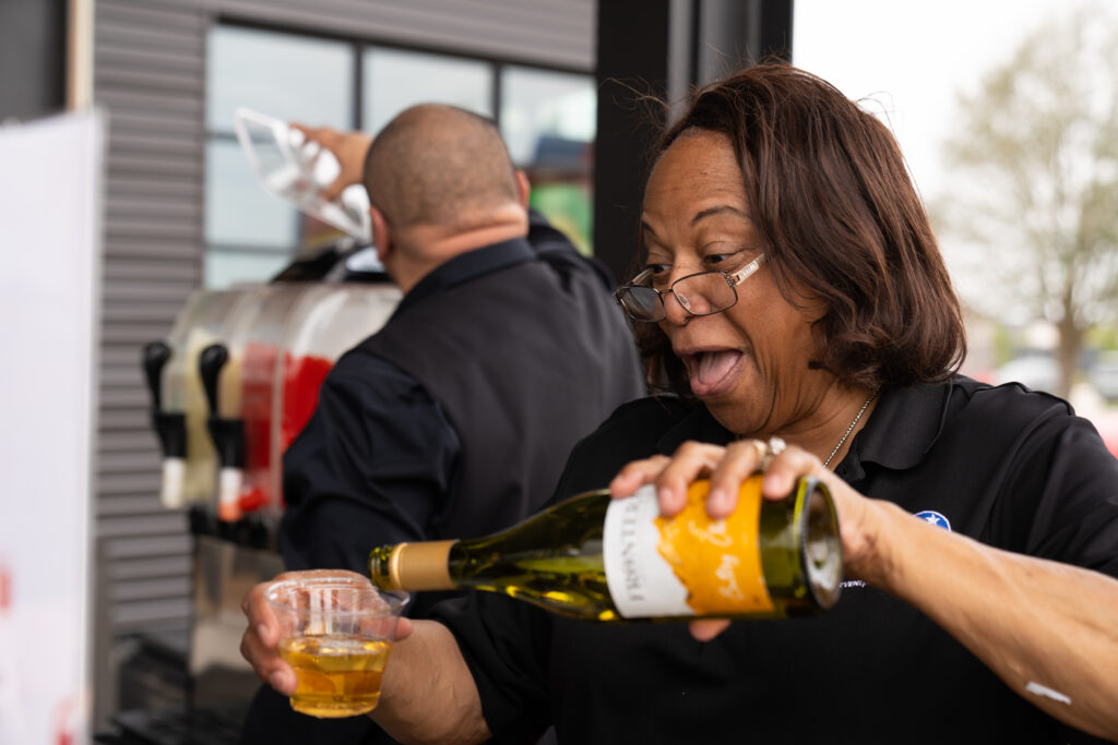 Event staff pours wine for adult guests at the beverage station during the Austin Point grand opening event.