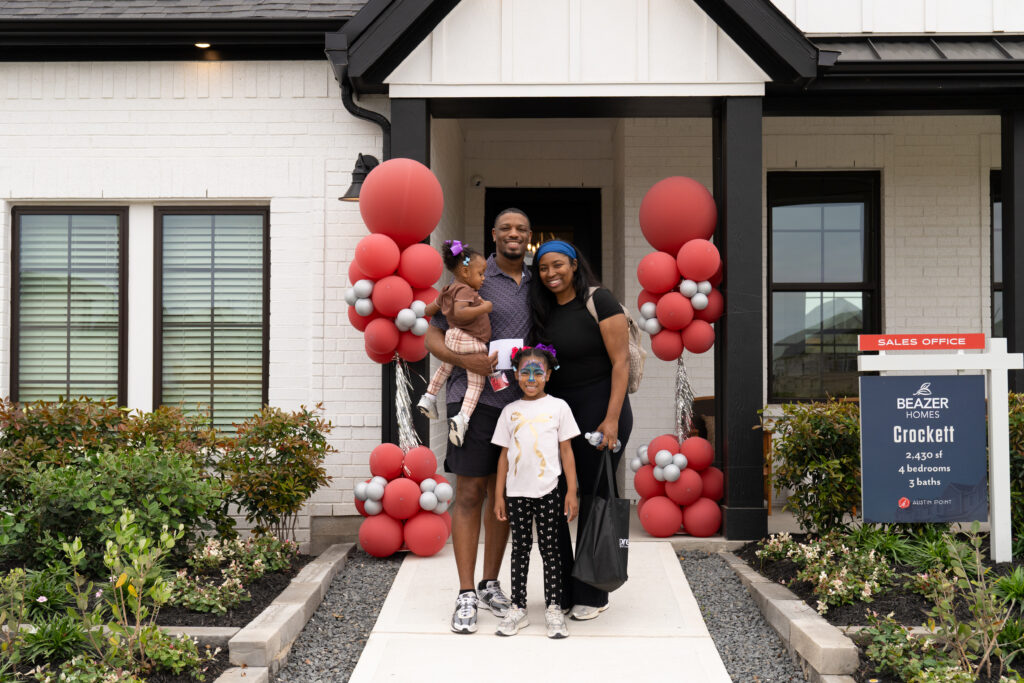 A family poses outside a Beazer Homes model during the Paint This Town Red grand opening at Austin Point.