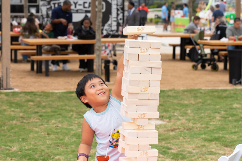 A child plays giant Jenga during the Paint This Town Red grand opening festival at Austin Point.